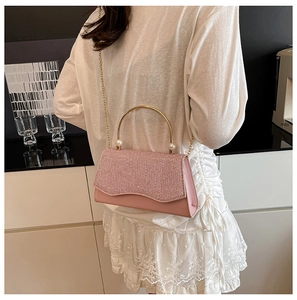 Détail du sac bandoulière rose à paillettes avec poignée dorée et ornements de perles