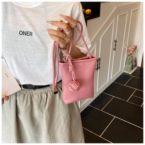 Dettaglio borsa a secchiello in pelle rosa con decorazione a nodo e tracolla lunga