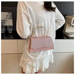 Détail du sac à paillettes roses avec poignée dorée, accents de perles et bandoulière