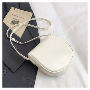 Detail of elegant cream saddle bag on fabric background with minimalist leather texture