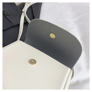 Close-up of white leather crossbody bag showing golden magnetic closure and inner lining