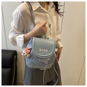 Detail of light blue denim mini backpack with white letter embroidery and plush doll charm