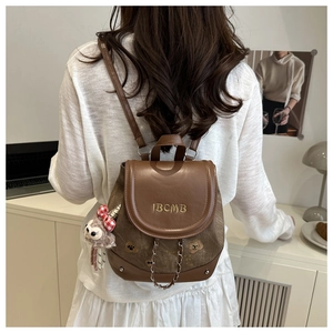Detail view of vintage brown backpack featuring IBCMB embroidery and plush lamb charm