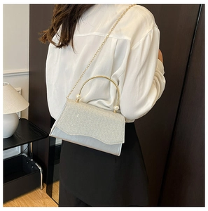 Détail du sac de soirée à paillettes argentées avec poignée dorée et perles