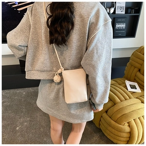 Detail of a creamy white litchi pattern mini crossbody bag with a thick knotted rope strap