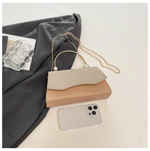 Sac à main beige chic avec rabat scintillant et poignée perle sur fond de costume gris