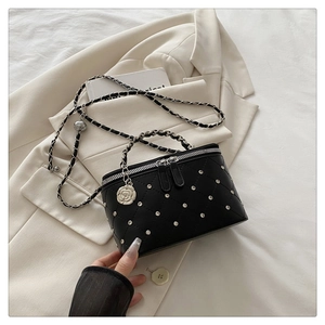 Detailed view of black quilted crossbody bag with studs and camellia charm accent