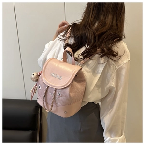 Détail d'un mini sac à dos rose avec cordon en chaîne et accessoire en peluche