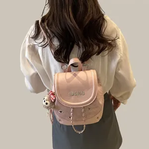 Detail view of pink mini backpack featuring IBCMB embroidery and a cute monkey charm