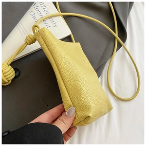 Macro view of bright yellow mini crossbody bag with textured lychee grain leather