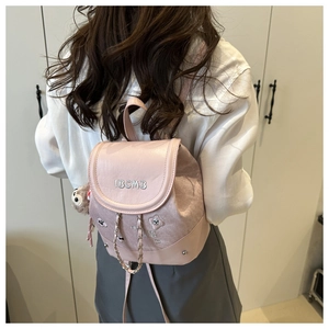 Détail du mini sac à dos rose clair avec broderie IBCMB et chaîne argentée sur modèle