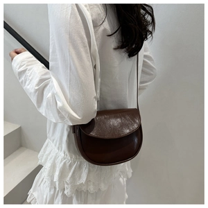 Model wearing dark brown saddle bag showing the sleek leather finish and minimalist strap