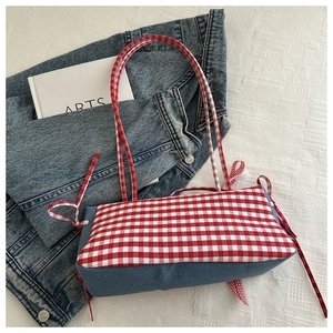 Detail of red gingham tote bag with denim patchwork and slender straps on casual attire