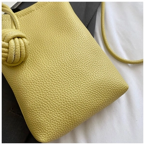 Detail of yellow lychee texture leather mini phone bag with knot decorative strap