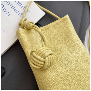 Detail of light yellow lychee grain leather handbag with woven rope knot decoration