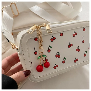 Detalle del bolso blanco rectangular con estampado de cerezas rojas y colgante de cereza