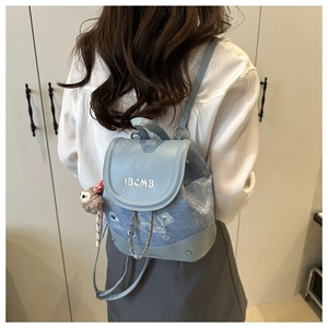 Detail view of light blue denim mini backpack with chain accents and plush toy charm