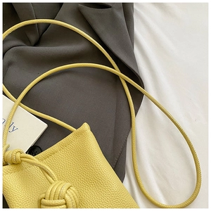 Detailed close-up of yellow lychee grain leather bucket bag with unique knotted strap detail