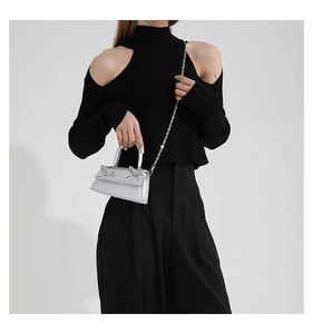 Detail of silver metallic ballet-style mini bag with bow accents and chain strap on model
