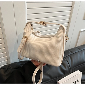 Gros plan sur la texture en velours côtelé crème et la boucle en métal doré du sac