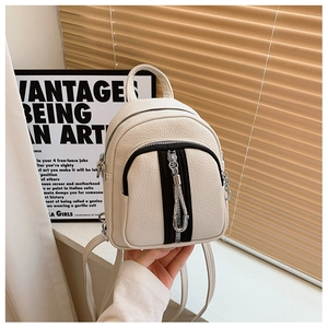 Detail eines cremeweißen Mini-Rucksacks mit Litschi-Textur und silbernem Reißverschluss