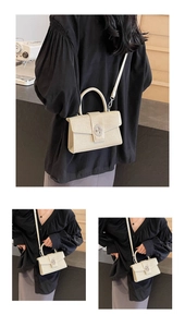 Detailed close-up of cream crocodile pattern bag with silver twist lock and handle