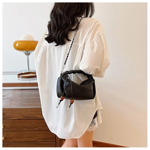 Détail du sac plissé noir avec bandoulière chaîne et accents de cordon perlé