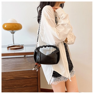 Détail du sac nuage plissé noir avec perles d'ambre, pompons et fine chaîne métallique