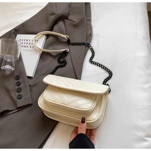 Detail view of cream V-quilted flap bag featuring black chain strap and multi-layer pockets