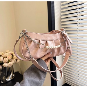 Détail du sac sous le bras rose gaufré croco avec chaîne cœur et perles blanches