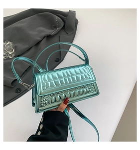 Detailed shot of teal crocodile embossed metallic handbag with polished hardware and strap