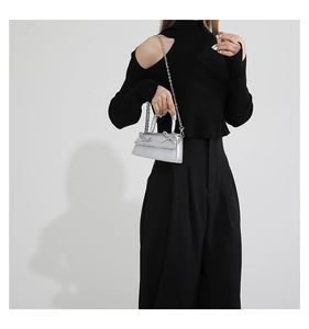 Chic silver mini crossbody bag with delicate bows shown on a black knit outfit