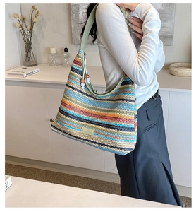 Close-up of rainbow striped woven tote bag with light green straps and logo detail