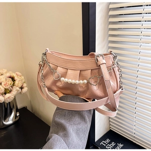 Détail du sac rose motif croco avec pendentifs cœur et chaîne de perles décorative