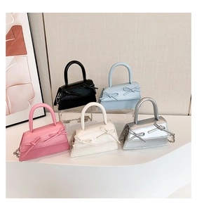 Detailed view of mini trapezoid handbags in various colors with bow decorations and chain straps