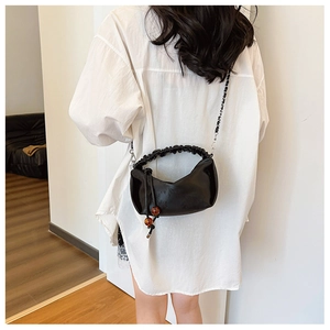 Détails d'un sac croissant noir avec poignée plissée nuage et accents de perles ambrées