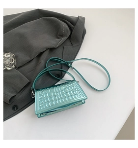 Detail of mint green crocodile embossed crossbody bag with metallic silver hardware