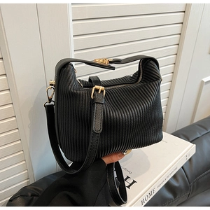 Détail d'un sac à bandoulière noir plissé avec fermeture éclair et finitions dorées
