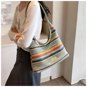 Detail of bohemian rainbow woven hobo bag with green handle and beaded charm accessory