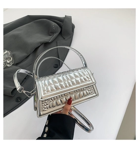 Detail of silver handbag featuring embossed grid texture and crocodile pattern finish