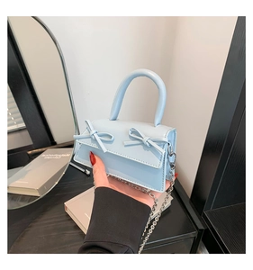 Detail of light blue mini handbag featuring twin bows and silver metal chain strap