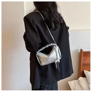 Sac à main argenté plissé avec motifs gaufrés et bandoulière chaîne porté par un mannequin