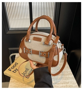 Close-up of contrast color patchwork leather Boston bag with metal buckle details