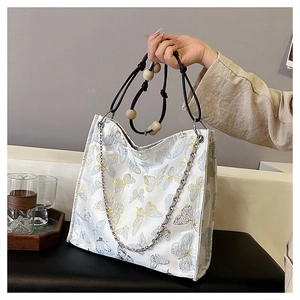 Detail der weißen Totebag mit Schmetterlingsstickerei, Holzperlengriff und Silberkette