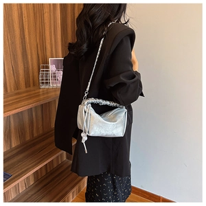 Sac bandoulière plissé argenté avec gaufrage floral et chaîne porté par un mannequin