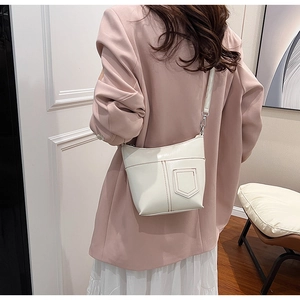 Detailansicht der cremefarbenen Hobo-Tasche mit dünnem Riemen und Silberhaken am Model