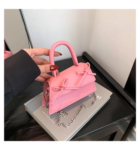 Detail of pink mini handbag with double bow decoration and silver metal chain strap