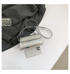 Detailed top view of silver textured handbag with metallic finish beside a smartphone