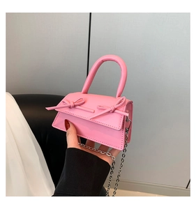 Detailed close-up of pink mini crossbody bag with glossy leather and bow details
