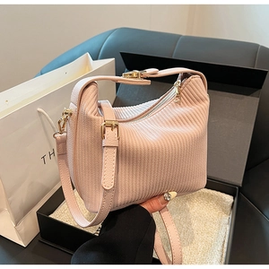 Détail du sac à main plissé rose avec ferrures dorées et emballage cadeau élégant